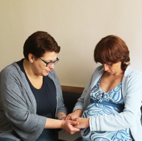 counselor praying with woman facing unplanned pregnancy in Ukraine